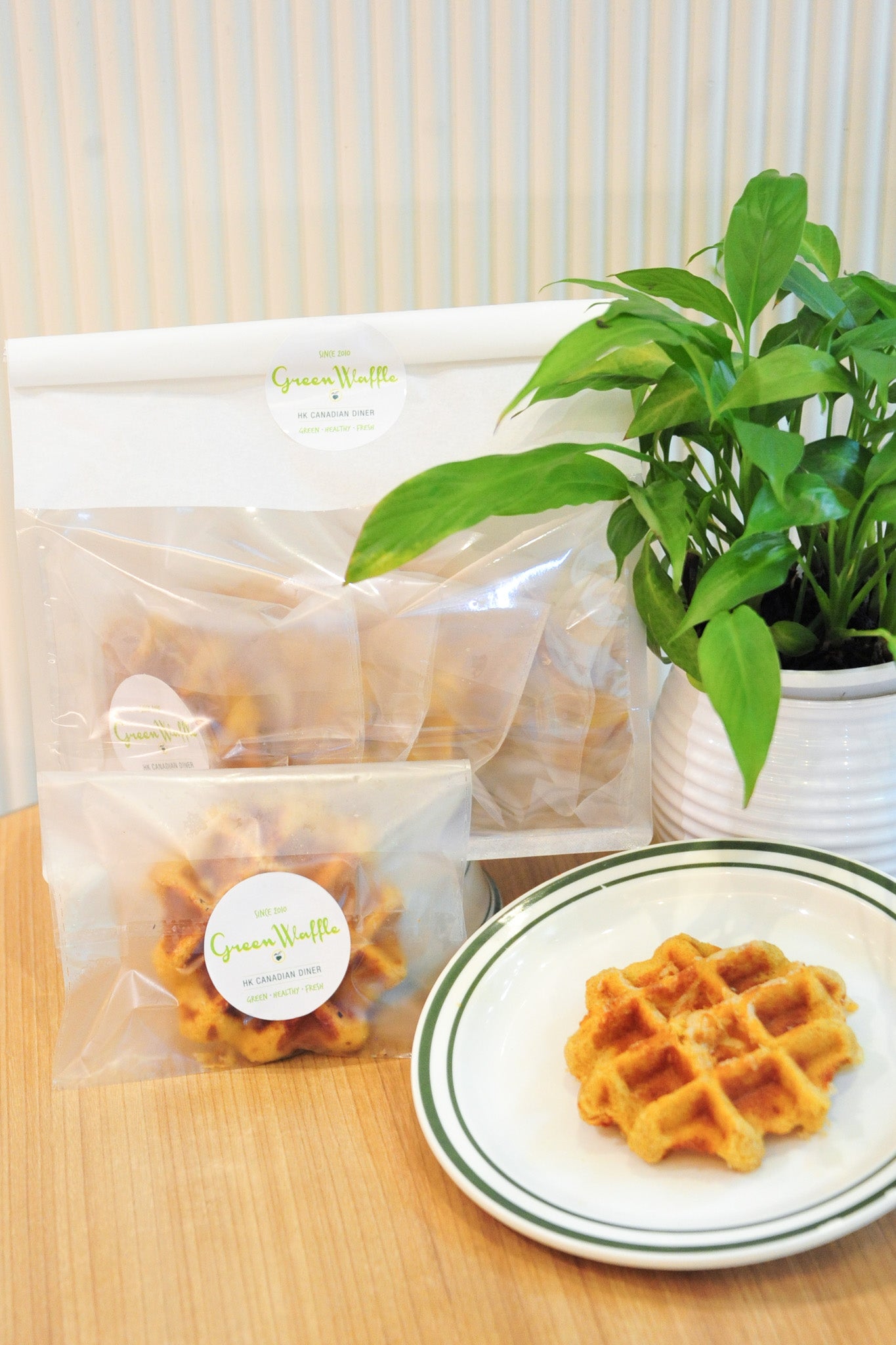 Packaged waffles on a wooden table with a plant in the background